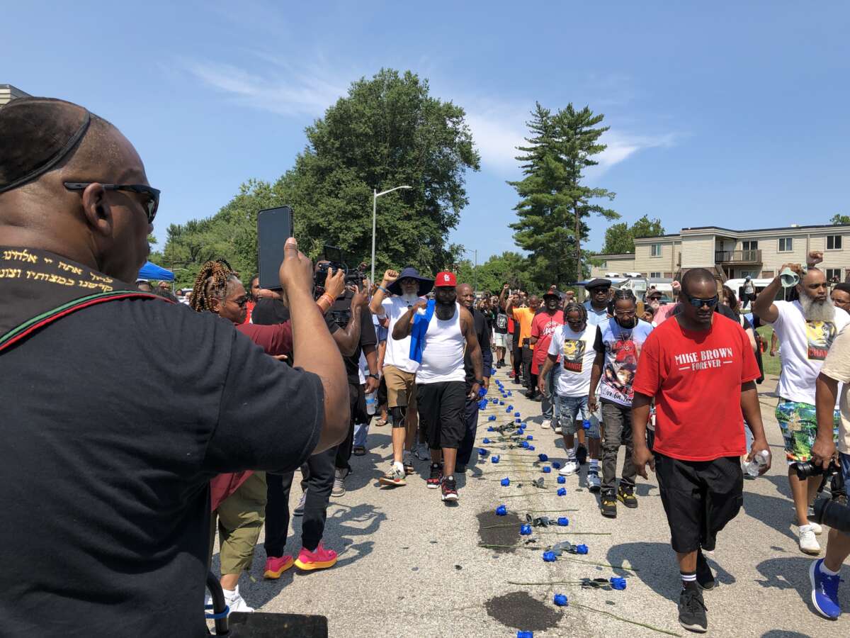 Après une marche de 4,5 milles de Normandy High School, où Mike Brown Jr. a obtenu son diplôme le 1er août 2014, la marche entre dans le tronçon à domicile. L'invité honoré Fred Hampton Jr. apparaît dans le béret à droite de Mike Brown Sr.